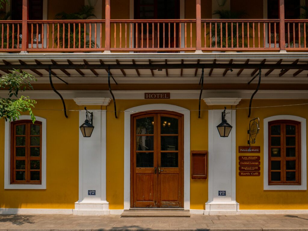 A beautifully preserved colonial hotel facade in Puducherry, India, showcasing vibrant colors and classic architecture.