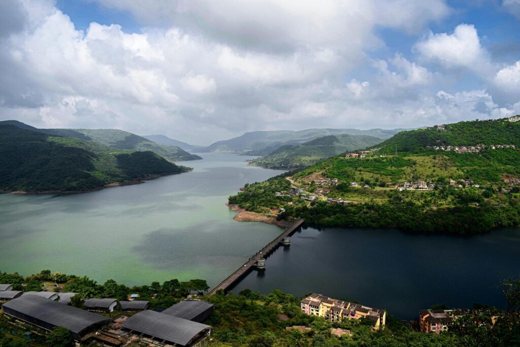 Aerial view showcasing a picturesque bridge crossing a serene river amidst lush green hills.